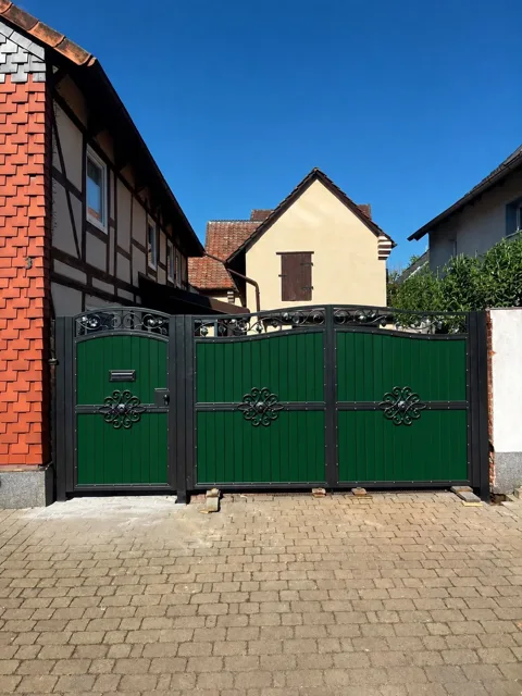 Grünes Tor mit dekorativen Metallbändern