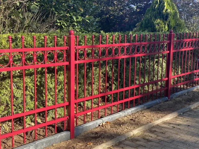 Roter Zaun mit senkrechten Stäben und dekorativen Details