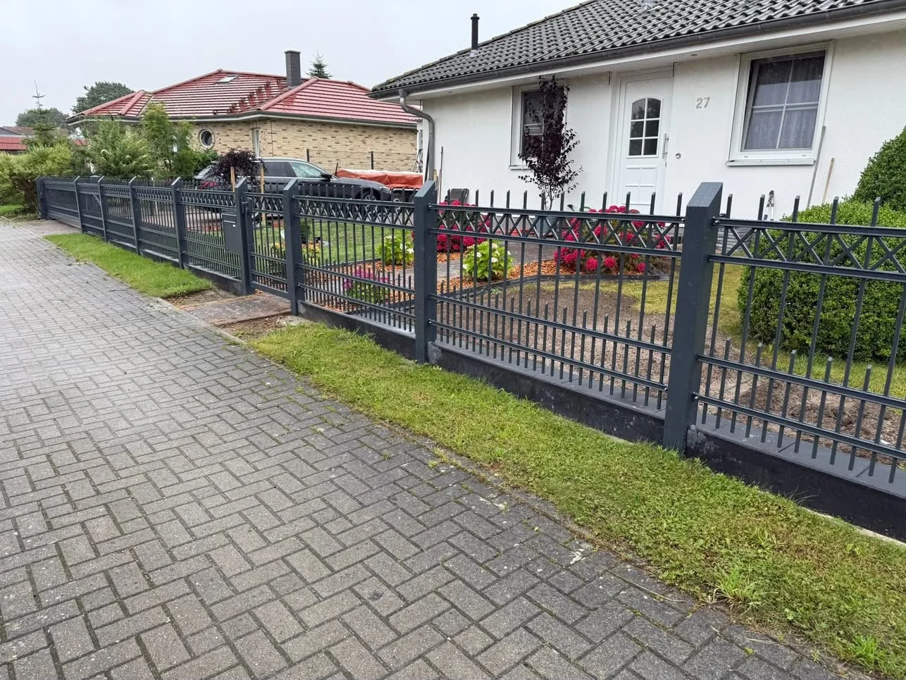 Metallzaun mit einem dekorativen Kreuzband an einem Wohnhaus
