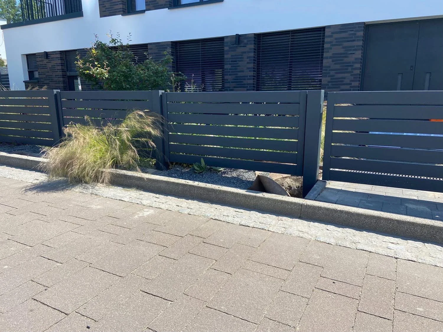 Anthrazitfarbene waagerechte Zaunfelder vor einer modernen Fassade